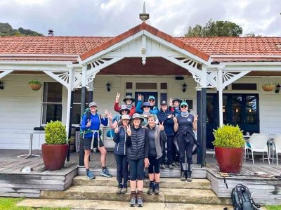 11 walkers are gathered on the steps out the front of Furneaux Lodge, New Zealand.